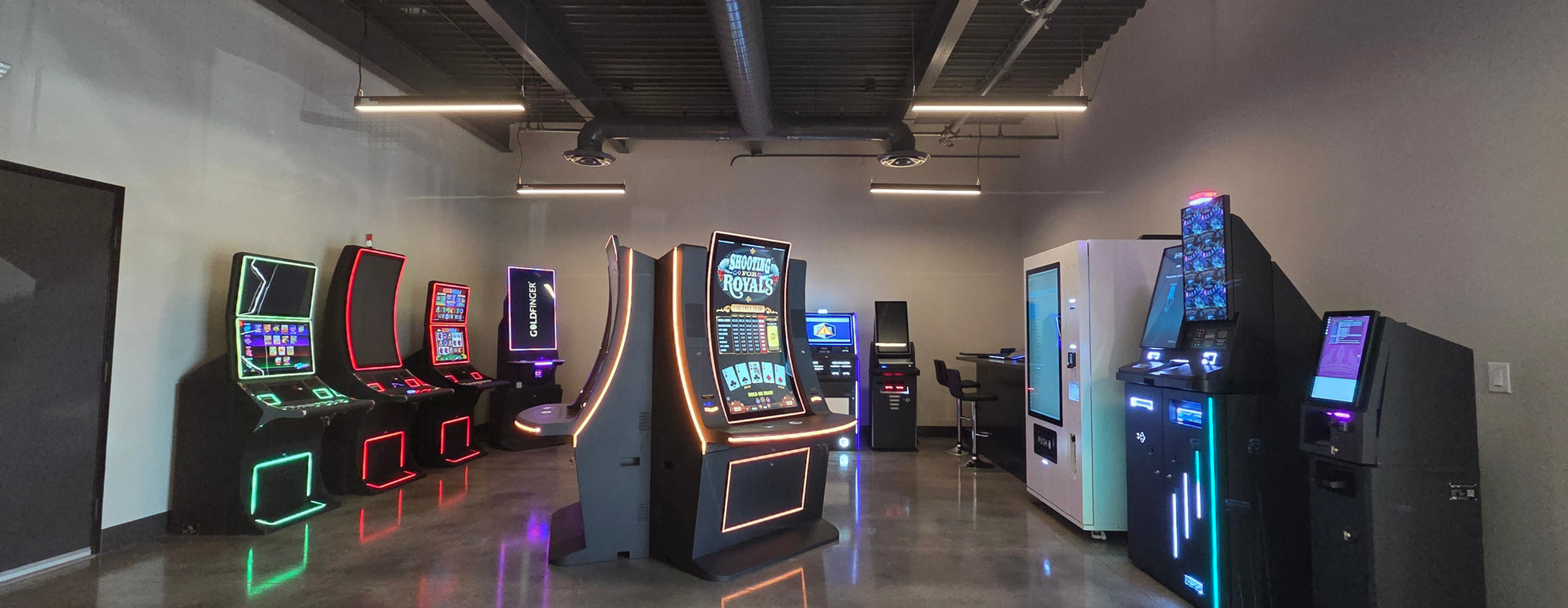 Dim showroom lined with gaming, sportsbook, and vending kiosks manufactured by Nevatronix