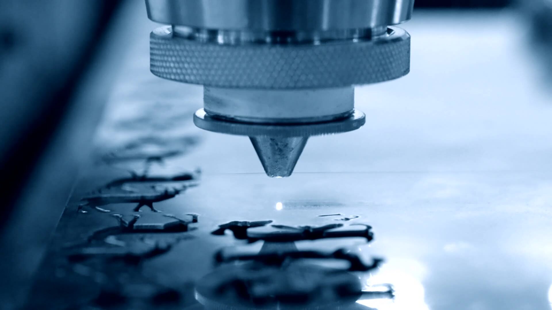 Close-up of a laser cutting head precisely cutting shapes from a flat sheet-metal blank