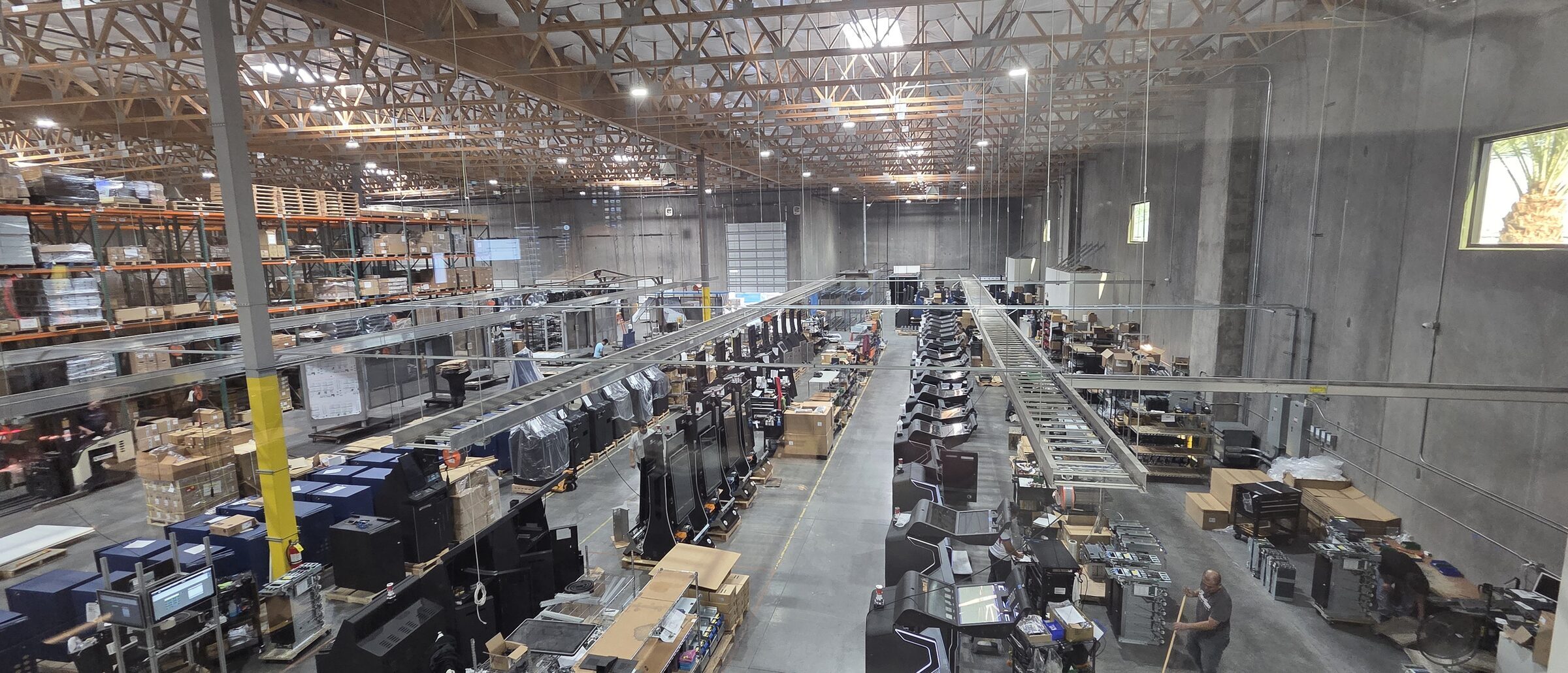 Nevatronix manufacturing floor with rows of gaming cabinets in assembly under a warehouse roof