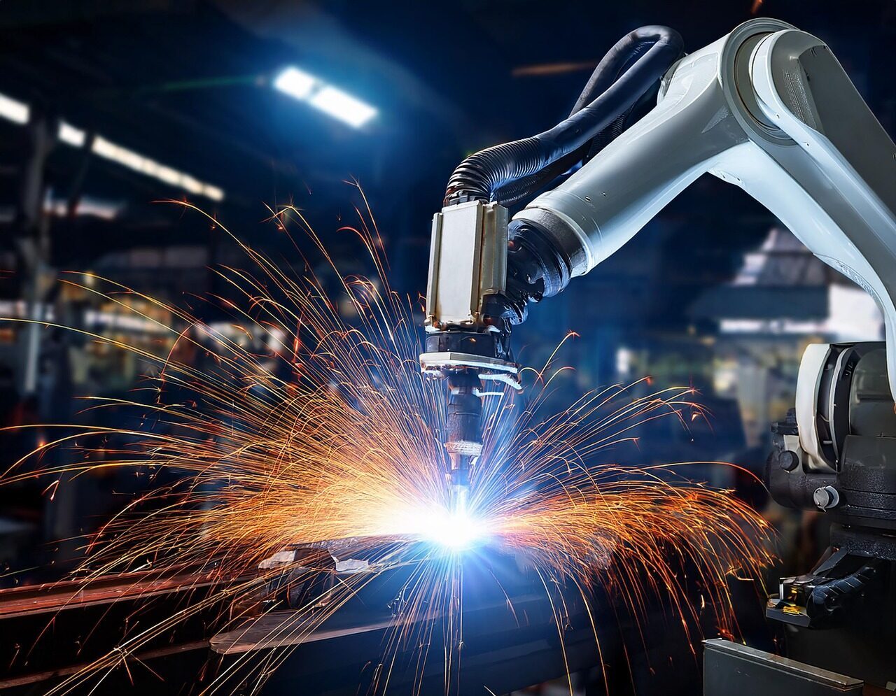Six-axis robotic arm welding a metal assembly with a spray of sparks in an automated production cell